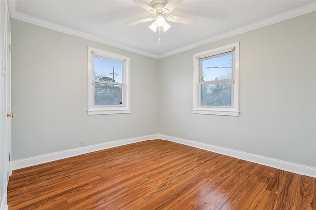 empty room featuring ornamental molding, baseboards, and wood finished floors