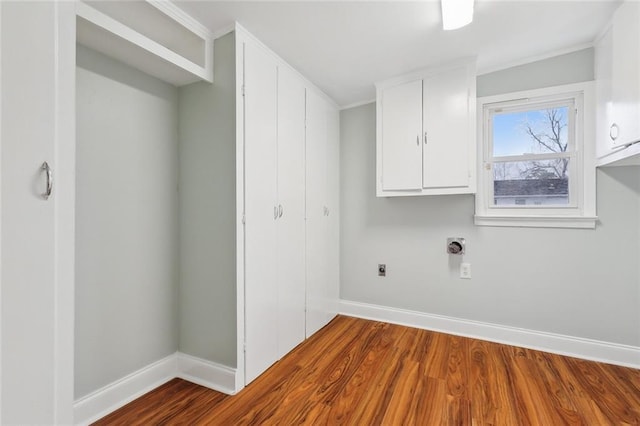 clothes washing area featuring cabinet space, wood finished floors, electric dryer hookup, and baseboards