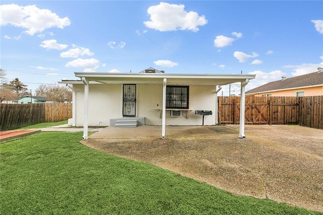 rear view of property featuring a lawn, fence private yard, and stucco siding