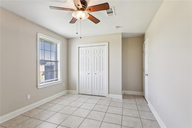 unfurnished bedroom with baseboards, visible vents, ceiling fan, a closet, and light tile patterned flooring