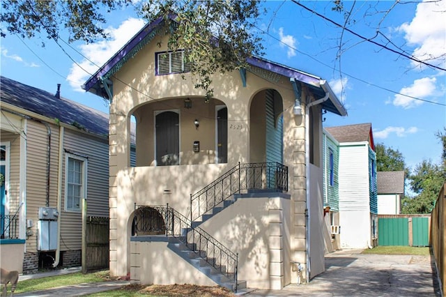 view of front facade featuring stairway, fence, and stucco siding