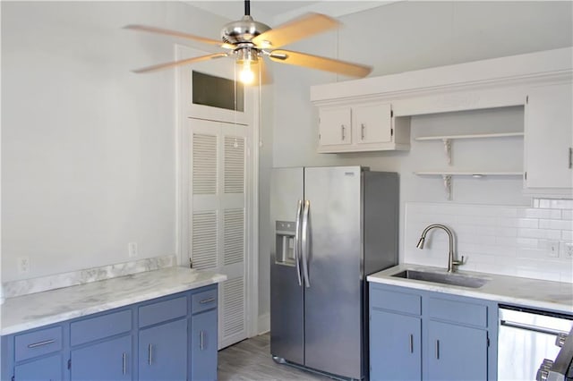 kitchen featuring stainless steel appliances, a sink, light countertops, blue cabinetry, and decorative backsplash