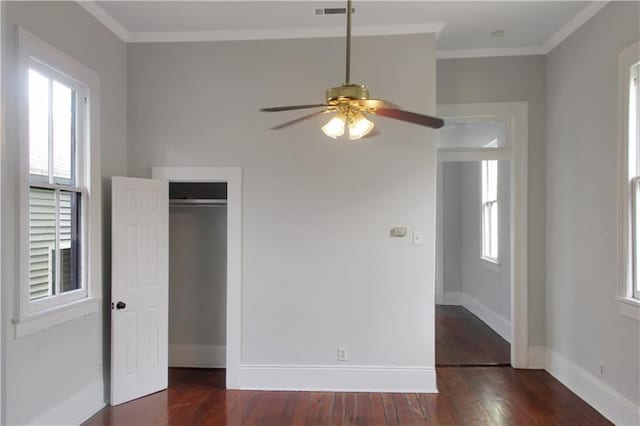 unfurnished bedroom with visible vents, multiple windows, ornamental molding, and dark wood-style flooring