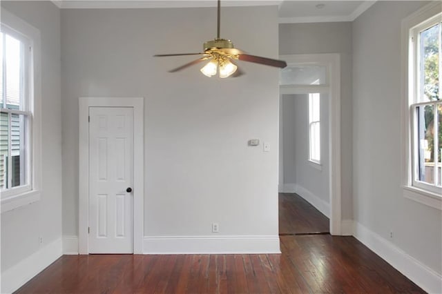 spare room with a ceiling fan, crown molding, baseboards, and dark wood-style flooring