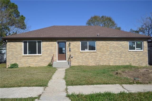 single story home featuring entry steps, a front yard, and brick siding