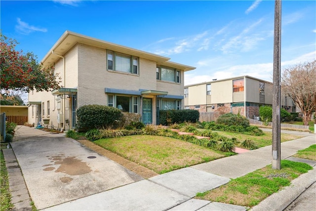 multi unit property featuring brick siding, a front yard, and fence