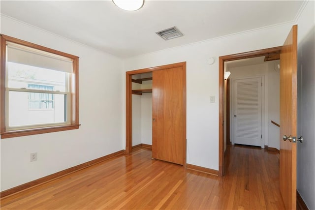 unfurnished bedroom with a closet, visible vents, baseboards, and wood finished floors