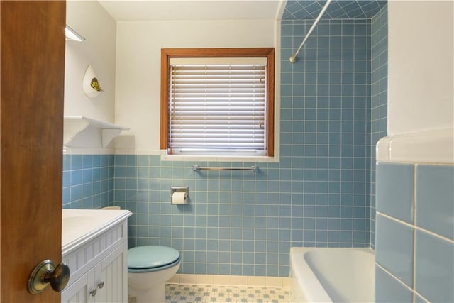 bathroom with toilet, tile patterned flooring, tub / shower combination, vanity, and tile walls