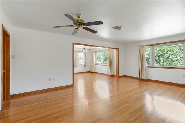 empty room featuring a wealth of natural light, visible vents, light wood-style flooring, and baseboards