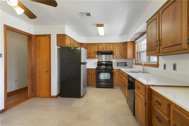 kitchen featuring brown cabinets, light countertops, visible vents, a sink, and black appliances