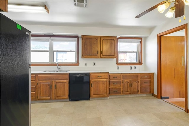 kitchen featuring black dishwasher, light countertops, visible vents, freestanding refrigerator, and a sink