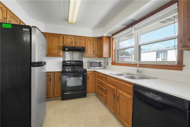 kitchen with black appliances, under cabinet range hood, light countertops, and a sink