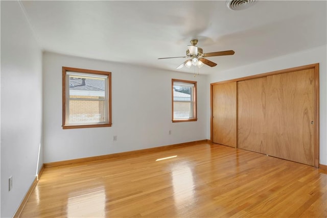 unfurnished bedroom featuring a ceiling fan, visible vents, baseboards, a closet, and light wood finished floors
