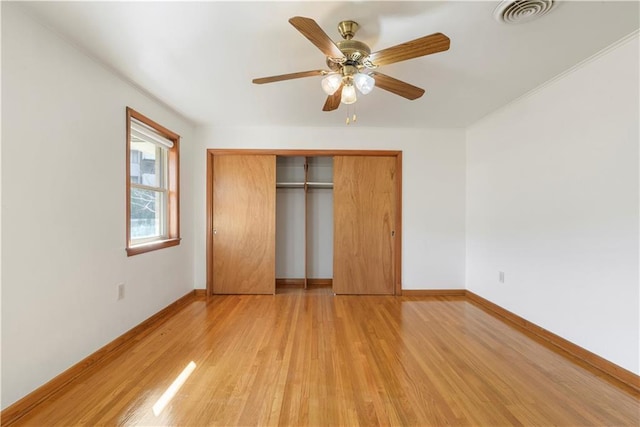 unfurnished bedroom featuring a ceiling fan, visible vents, baseboards, a closet, and light wood-type flooring
