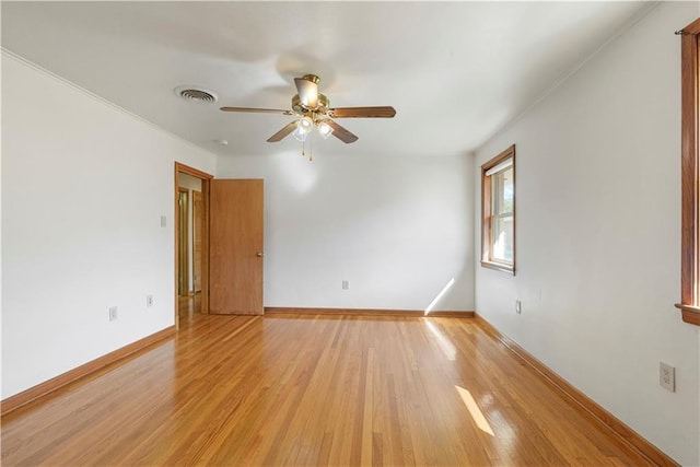 unfurnished room with a ceiling fan, light wood-type flooring, visible vents, and baseboards