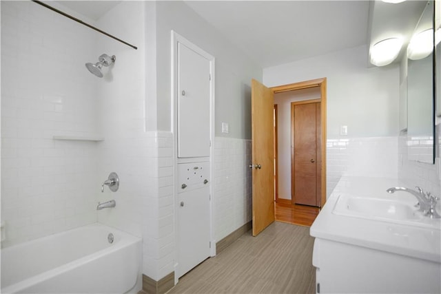 full bath with double vanity, tile walls, a sink, a closet, and shower / bathing tub combination