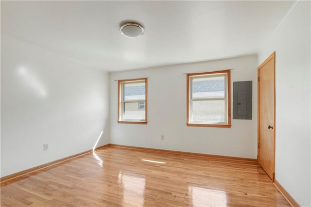 unfurnished room featuring light wood-style floors, electric panel, and baseboards