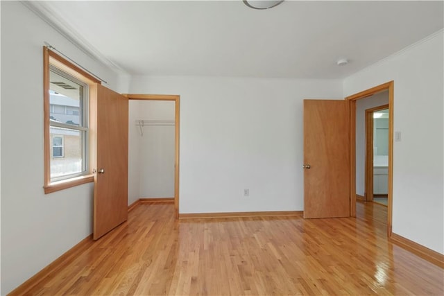 unfurnished bedroom featuring crown molding, a closet, light wood-type flooring, and baseboards