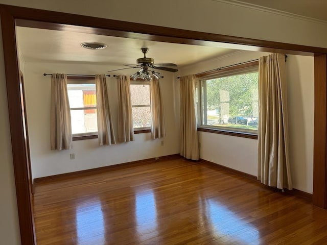 unfurnished room featuring baseboards, wood finished floors, and a healthy amount of sunlight