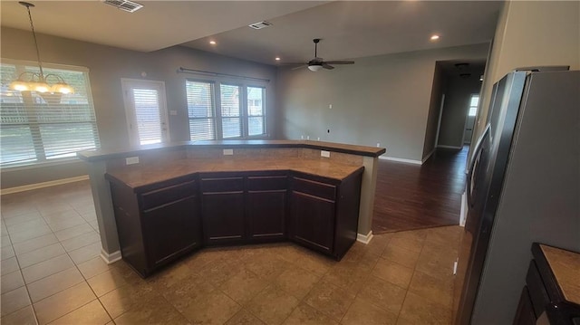 kitchen featuring dark countertops, freestanding refrigerator, open floor plan, tile patterned flooring, and ceiling fan with notable chandelier