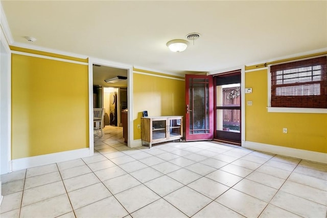 spare room with light tile patterned floors, visible vents, and crown molding