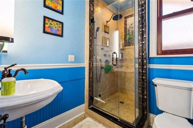 full bathroom featuring a stall shower, a sink, toilet, and baseboards