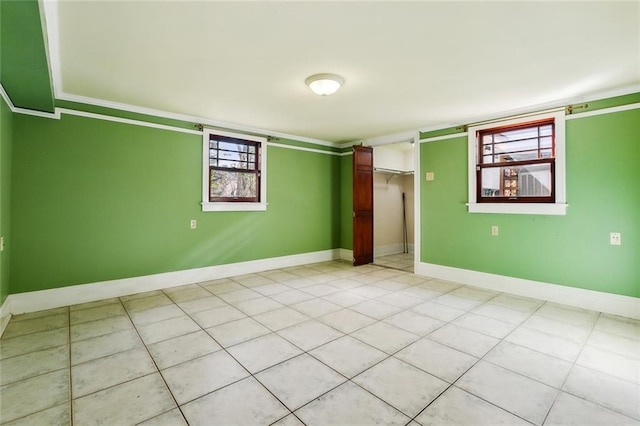 unfurnished bedroom featuring light tile patterned floors, a closet, baseboards, and crown molding