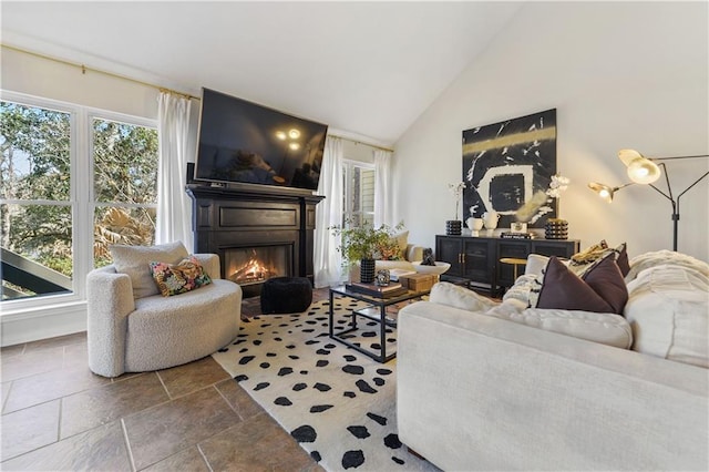 living room featuring high vaulted ceiling and a glass covered fireplace