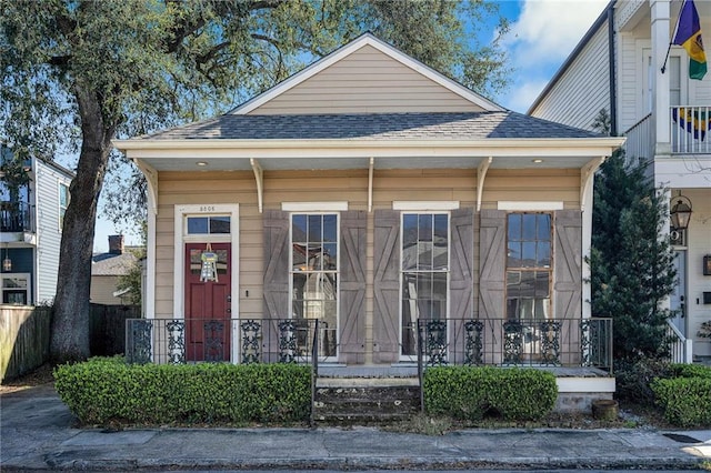 view of front facade featuring roof with shingles and fence