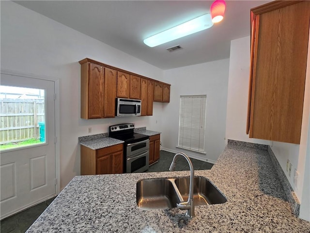 kitchen featuring stainless steel appliances, brown cabinets, visible vents, and light stone countertops