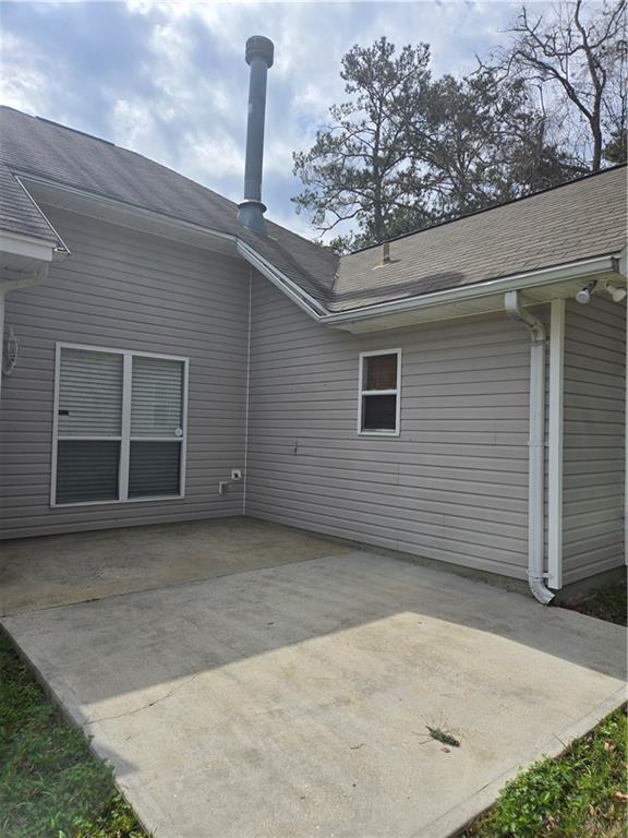 back of property with a patio and roof with shingles