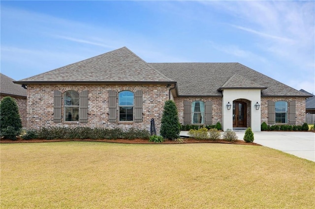 french country home with a front lawn and brick siding