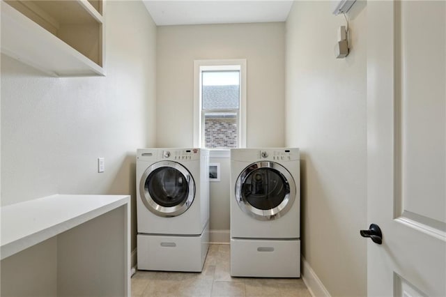 clothes washing area featuring laundry area, washer and clothes dryer, light tile patterned flooring, and baseboards