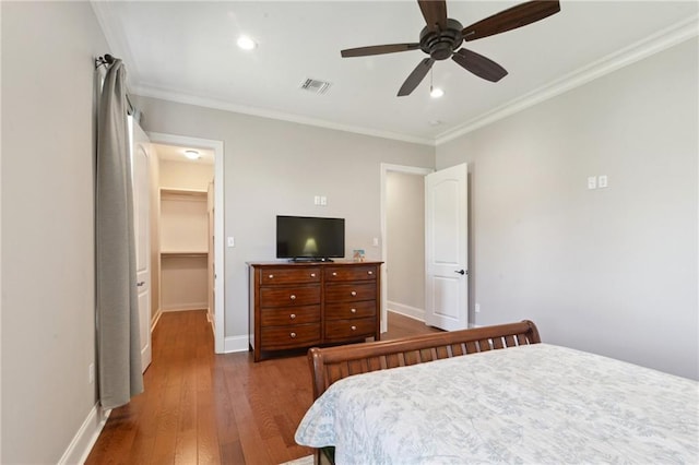 bedroom featuring crown molding, dark wood finished floors, a spacious closet, and baseboards