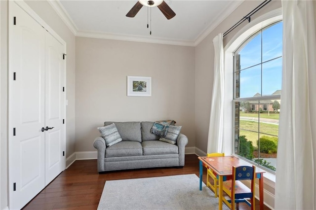 living area with ornamental molding, dark wood-style flooring, and baseboards