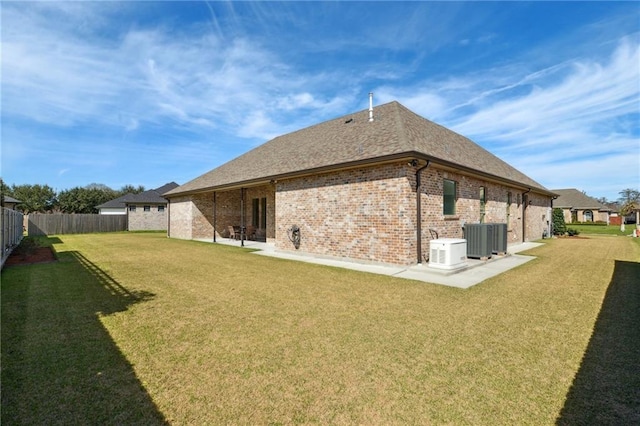 back of property with brick siding, a lawn, central AC, a patio area, and a fenced backyard