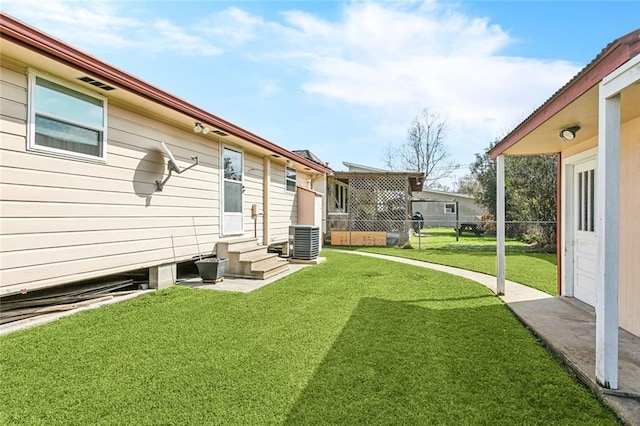 view of yard featuring entry steps, fence, and central AC