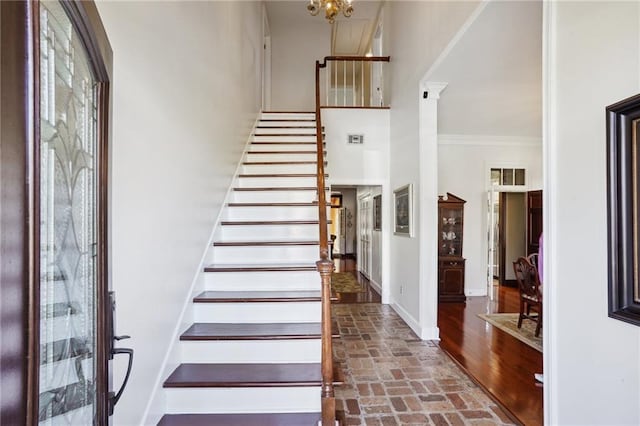 entryway featuring brick floor, stairs, baseboards, and ornamental molding