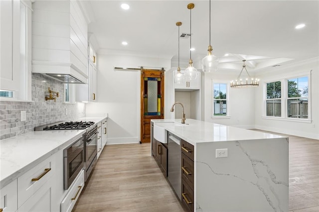 kitchen with recessed lighting, backsplash, a barn door, appliances with stainless steel finishes, and a sink
