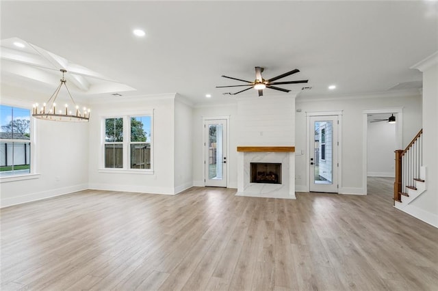 unfurnished living room with crown molding, a high end fireplace, and ceiling fan with notable chandelier