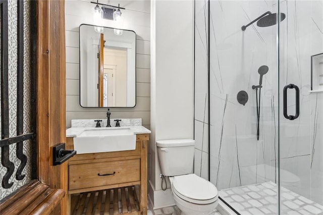 bathroom featuring toilet, a marble finish shower, and vanity