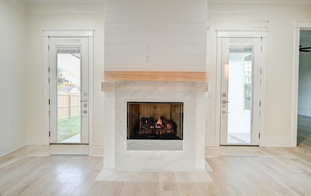 unfurnished living room with baseboards, a premium fireplace, and wood finished floors