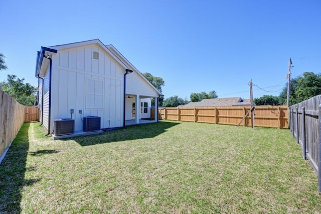 back of property with cooling unit, board and batten siding, a fenced backyard, and a lawn