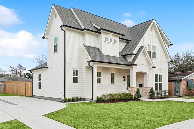 modern inspired farmhouse featuring board and batten siding, a shingled roof, fence, and a front lawn