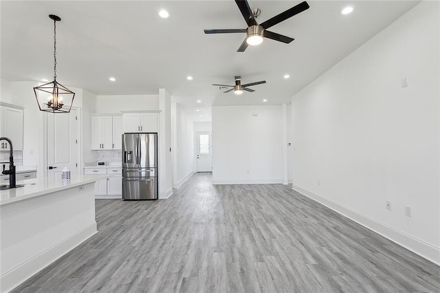 kitchen with light wood-style floors, open floor plan, light countertops, white cabinets, and stainless steel refrigerator with ice dispenser