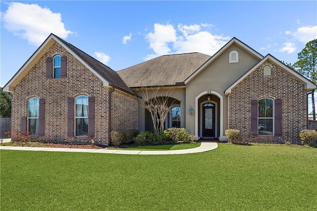 view of front facade featuring a front lawn, brick siding, and stucco siding