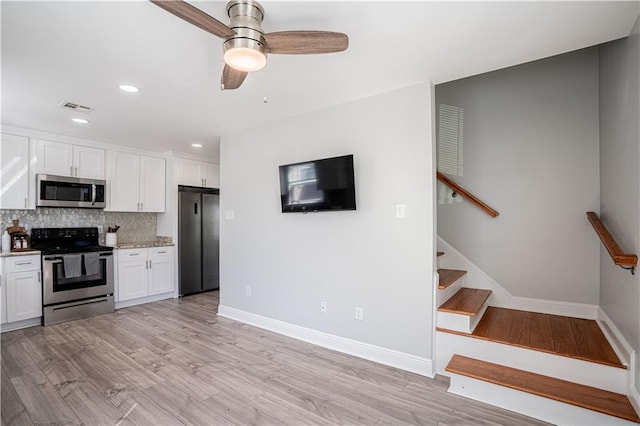 kitchen featuring light wood finished floors, visible vents, white cabinets, decorative backsplash, and stainless steel appliances