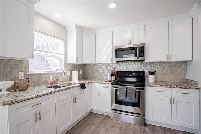 kitchen with stainless steel appliances, a sink, white cabinetry, and light wood-style floors