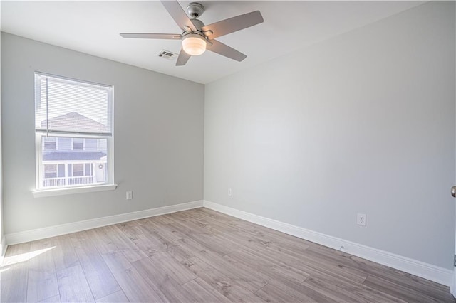 unfurnished room with a ceiling fan, visible vents, light wood-style flooring, and baseboards