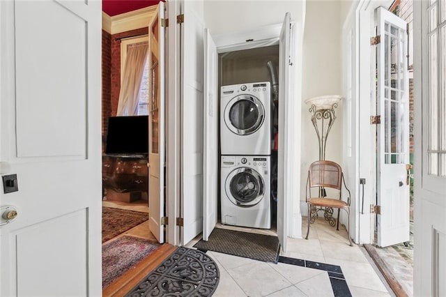 washroom featuring laundry area, stacked washer and clothes dryer, and light tile patterned flooring